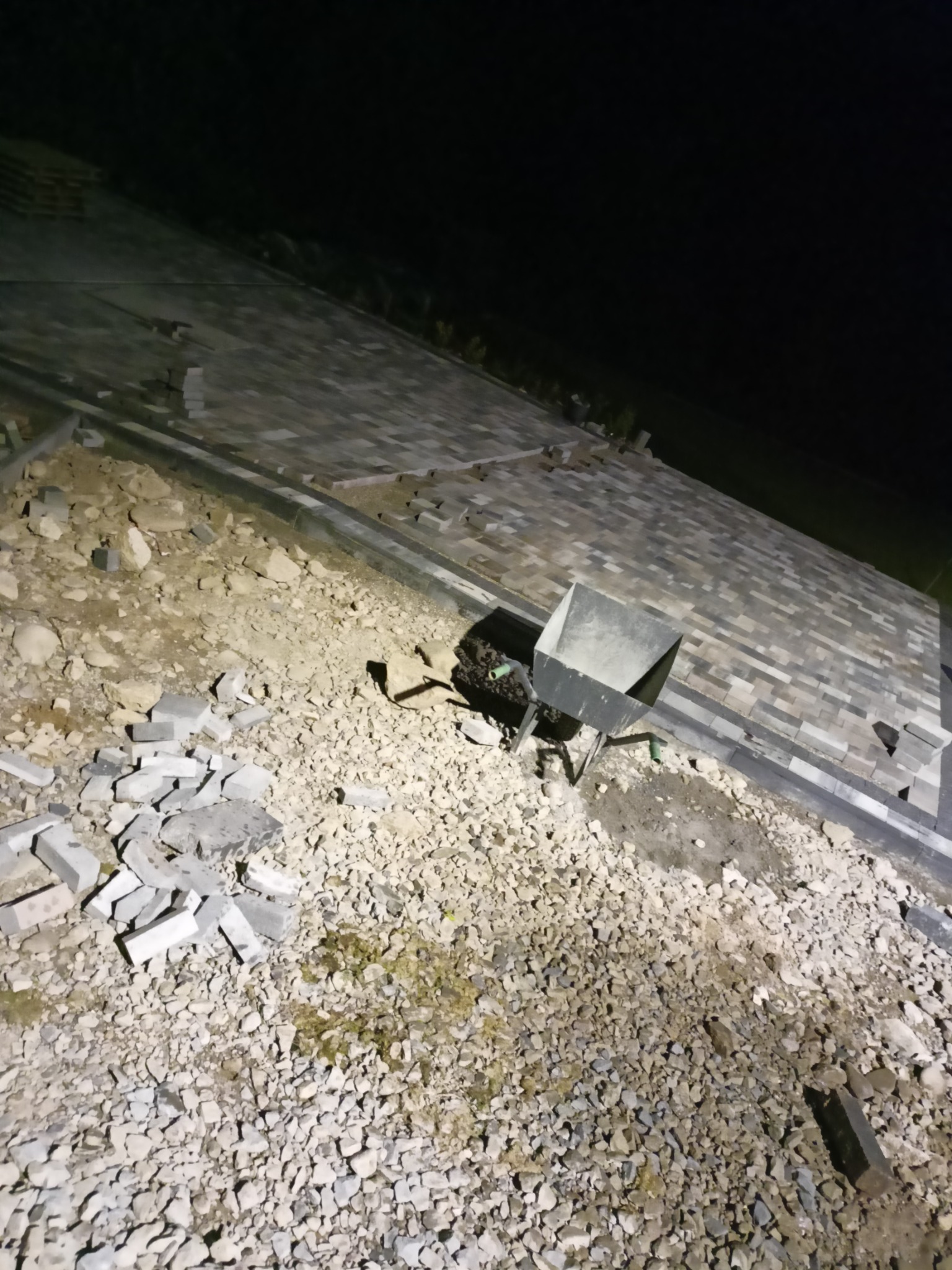 Układanie kostki brukowej w Nowym Sączu w trakcie realizacji, widoczna taczka i rozsypana kostka na podłożu.