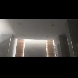 Nowoczesna łazienka z podświetlanymi panelami drewnopodobnymi na ścianie, szare ściany wykończone betonem architektonicznym, oświetlenie sufitowe punktowe, oraz grzejnik drabinkowy.