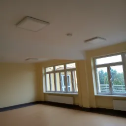 Wnętrze nowo wykończonego pomieszczenia z dwoma oknami, panelami LED w suficie i beżową podłogą, widok na zewnątrz przez okna.