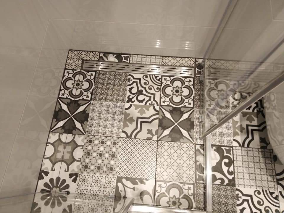 Wzór patchworkowy płytek podłogowych w kabinie prysznicowej z odpływem liniowym, widok z góry.