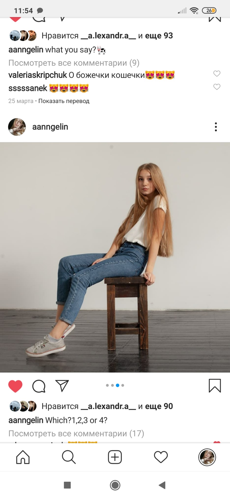 Młoda kobieta z długimi blond włosami siedzi na drewnianym stołku, ubrana w jeansy i białą koszulkę, pozuje na jasnym tle.