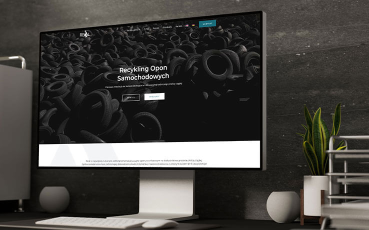 Ekran monitora prezentuje stronę internetową Reoil.pl z motywem recyklingu opon samochodowych. Minimalistyczne biurko z klawiaturą i rośliną w tle.