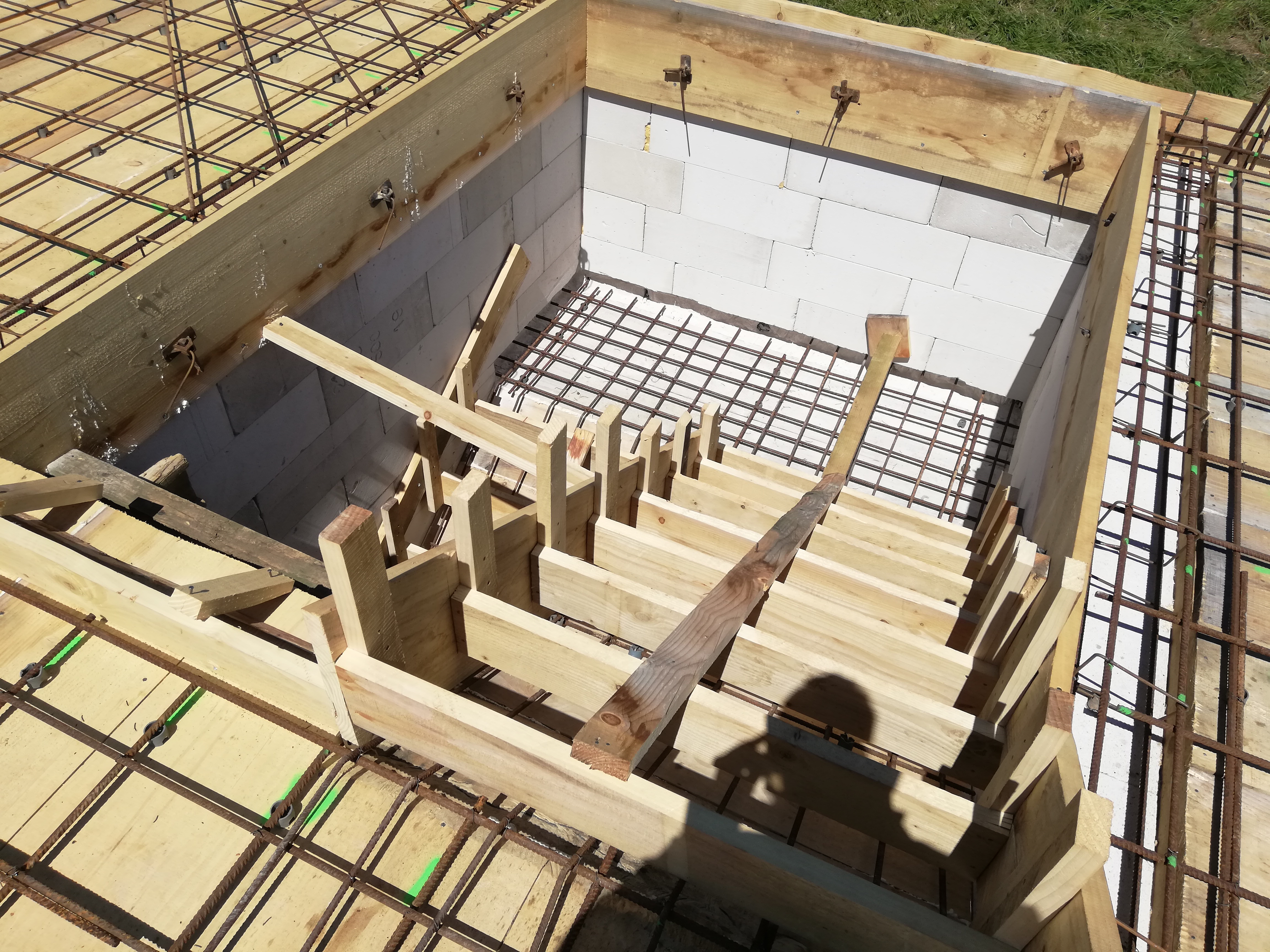 Szalunek i zbrojenie na płycie fundamentowej z bloczków betonowych, widok z góry, jasne drewno szalunku