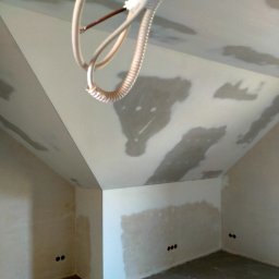 usługi remontowo wykończeniowe Paweł Paprocki - Poddasze w trakcie prac wykończeniowych: ściany i sufit częściowo pokryte gładzią, widoczne kable elektryczne. Stan surowy z elementami wykończenia.