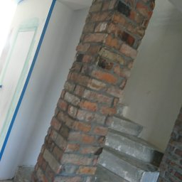 Przemysław Kamiński - Ściana zabezpieczona niebieską taśmą malarską przed malowaniem, widoczny fragment ceglanej kolumny i schodów w tle kuchnia z kolorową mozaiką.