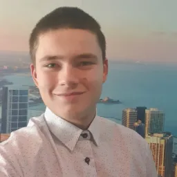 Portret młodego mężczyzny w koszuli na tle panoramy miasta z widokiem na morze.