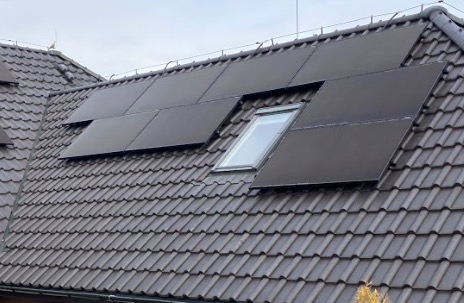 Czarne panele słoneczne Hyundai na skośnym dachu z dachówki ceramicznej, z oknem dachowym pośrodku instalacji.