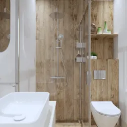 Nowoczesna łazienka z drewnopodobnymi płytkami, kabiną prysznicową typu walk-in, owalnym lustrem i umywalką nablatową na pierwszym planie.