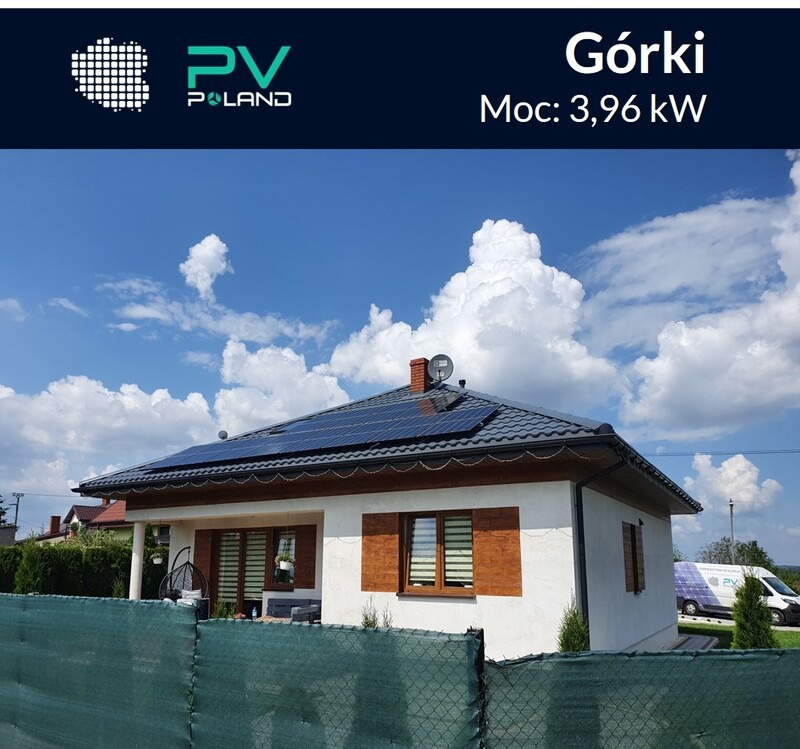 Dom jednorodzinny z panelami słonecznymi na dachu, widok zza ogrodzenia, błękitne niebo z obłokami w tle, na podjeździe zaparkowany bus firmy instalującej panele.