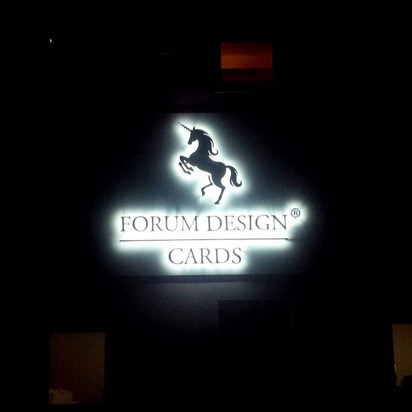 Podświetlane logo firmy Forum Design Cards z sylwetką jednorożca na czarnym tle.