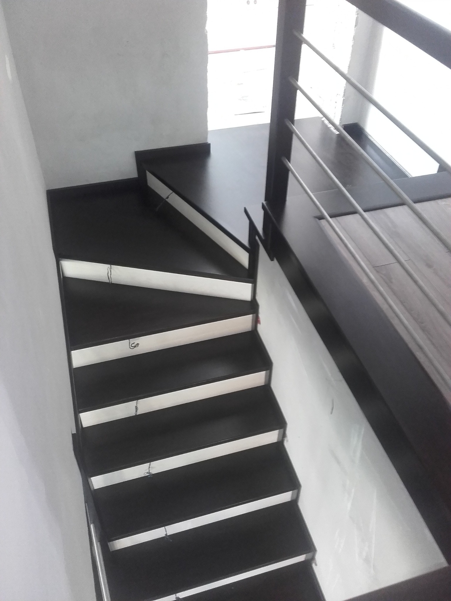 Nowoczesne, ciemne schody z białymi podstopnicami i metalową balustradą, widok z góry.