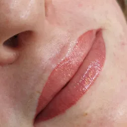 Bliski kadr na usta po zabiegu makijażu permanentnego w Brzesku, widoczne delikatne zaczerwienienie skóry wokół ust i błyszczący pigment.