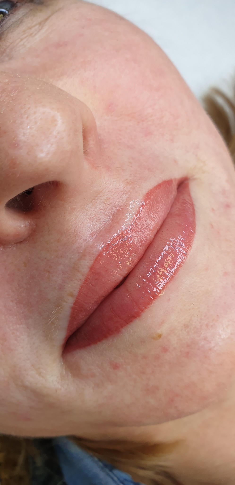 Bliski kadr na usta po zabiegu makijażu permanentnego w Brzesku, widoczne delikatne zaczerwienienie skóry wokół ust i błyszczący pigment.