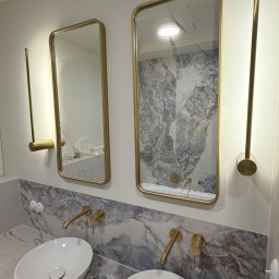 ProDremont Dmytro Nimenko - Nowoczesna łazienka z dwoma umywalkami nablatowymi, złotymi bateriami i lustrami w złotych ramach. Marmurowy blat i ściana dodają elegancji.