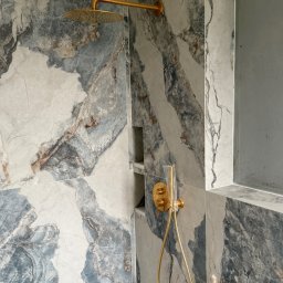 ProDremont Dmytro Nimenko - Wykończona łazienka z marmurowymi płytkami w odcieniach szarości i błękitu. Złota armatura, wnęka w ścianie. Minimalistyczny design, nowoczesne wykończenie.