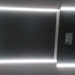 Szara ściana z wbudowanym oświetleniem LED, widoczny fragment instalacji elektrycznej w puszce.