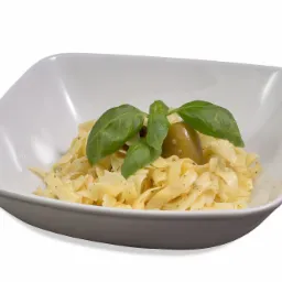 Tagliatelle w białym, kwadratowym naczyniu, udekorowane oliwką i świeżą bazylią, na białym tle.