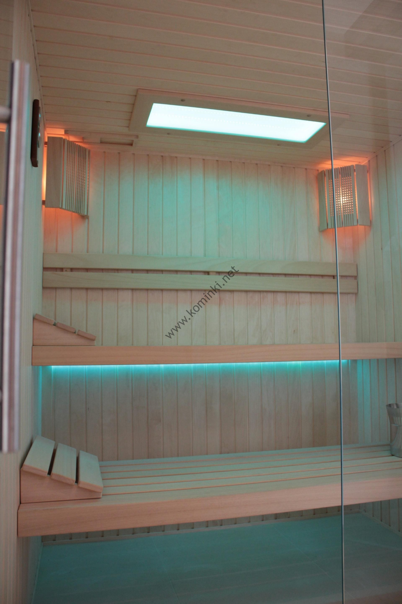 Wnętrze sauny z drewnianymi ławkami i oświetleniem LED, widok przez szklane drzwi.