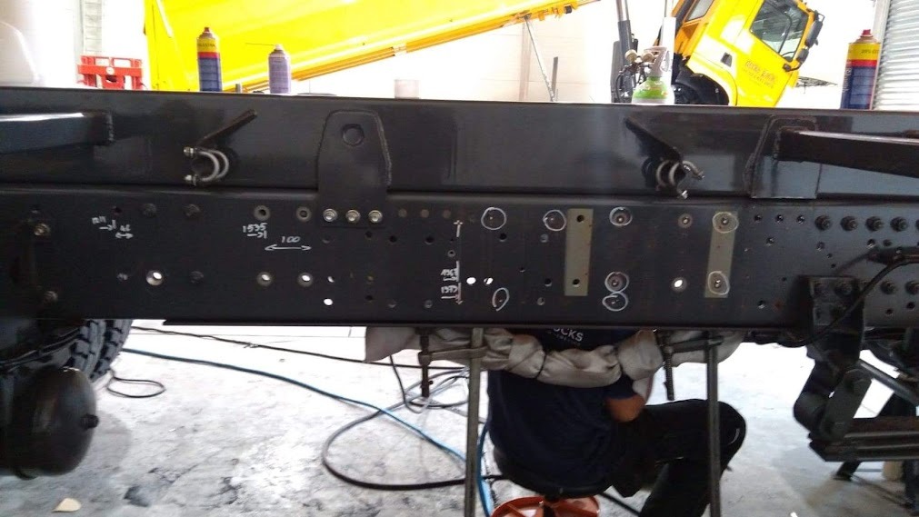 Spawanie ramy pojazdu ciężarowego; widoczne oznaczenia pomiarowe i ślady spawania