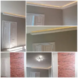 Wykończone wnętrze: szara ściana, białe drzwi dwuskrzydłowe, sufit z oświetleniem LED w listwie, dekoracyjna ściana z cegły.