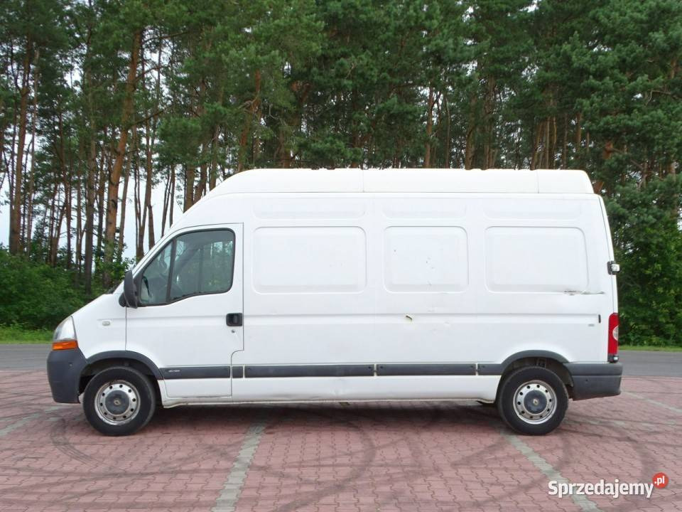 Biały, wysoki furgon Renault Master, sfotografowany z boku na tle drzew i czerwonej kostki brukowej.