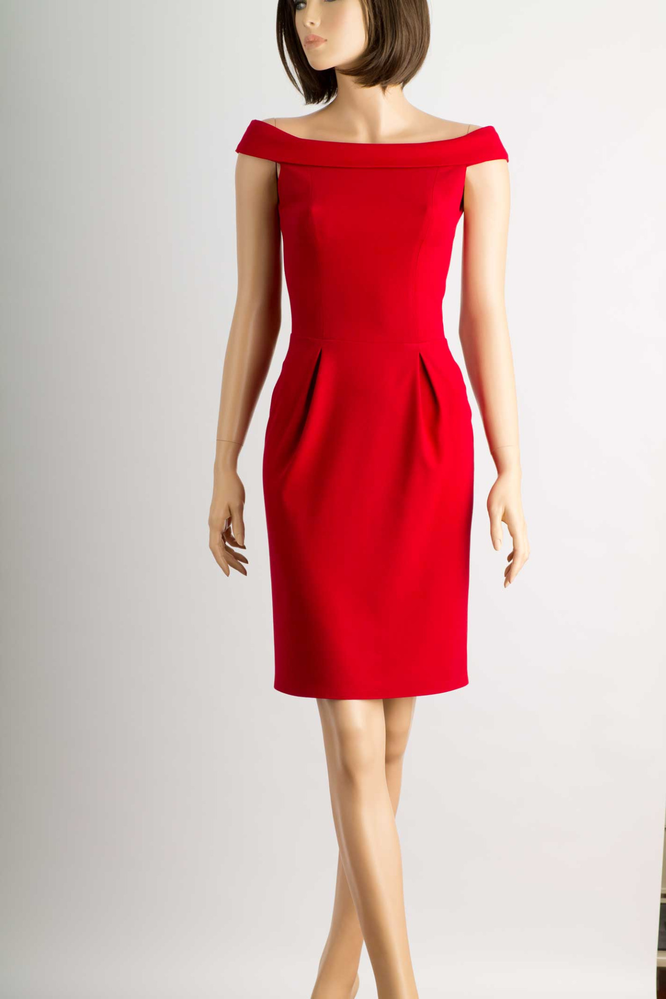 Czerwona, dopasowana sukienka z odkrytymi ramionami, prezentowana na manekinie na jasnym tle.