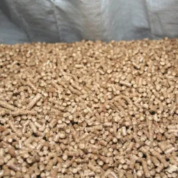 Jasnobrązowy pellet drzewny w worku, widoczne drobne fragmenty drewna w strukturze pelletu.