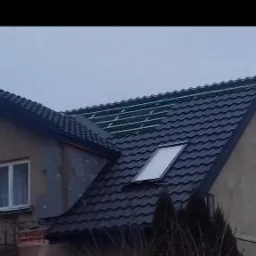 Częściowo pokryty, grafitowy dach z oknem połaciowym we Włocławku, widoczne elementy konstrukcji dachu w trakcie krycia.