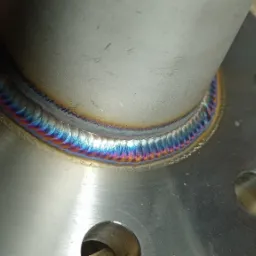 Spoina pierścieniowa rury ze stalową flanszą, wykonana w Leśnej Podlaskiej, z widocznymi kolorami hartowania.