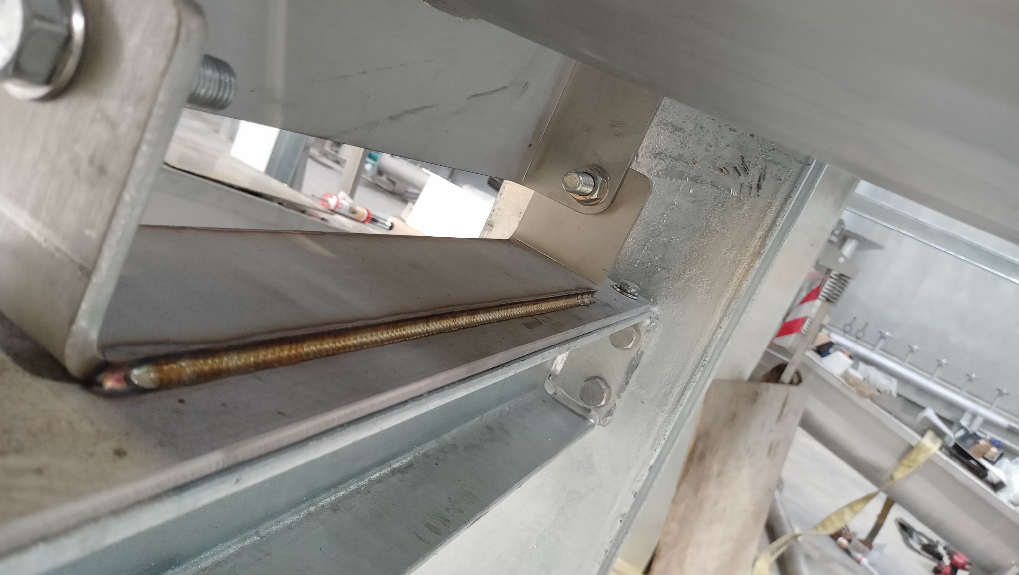 Spoina na metalowej konstrukcji, widoczne ślady po spawaniu, mocowanie śrubami, surowe wykończenie.