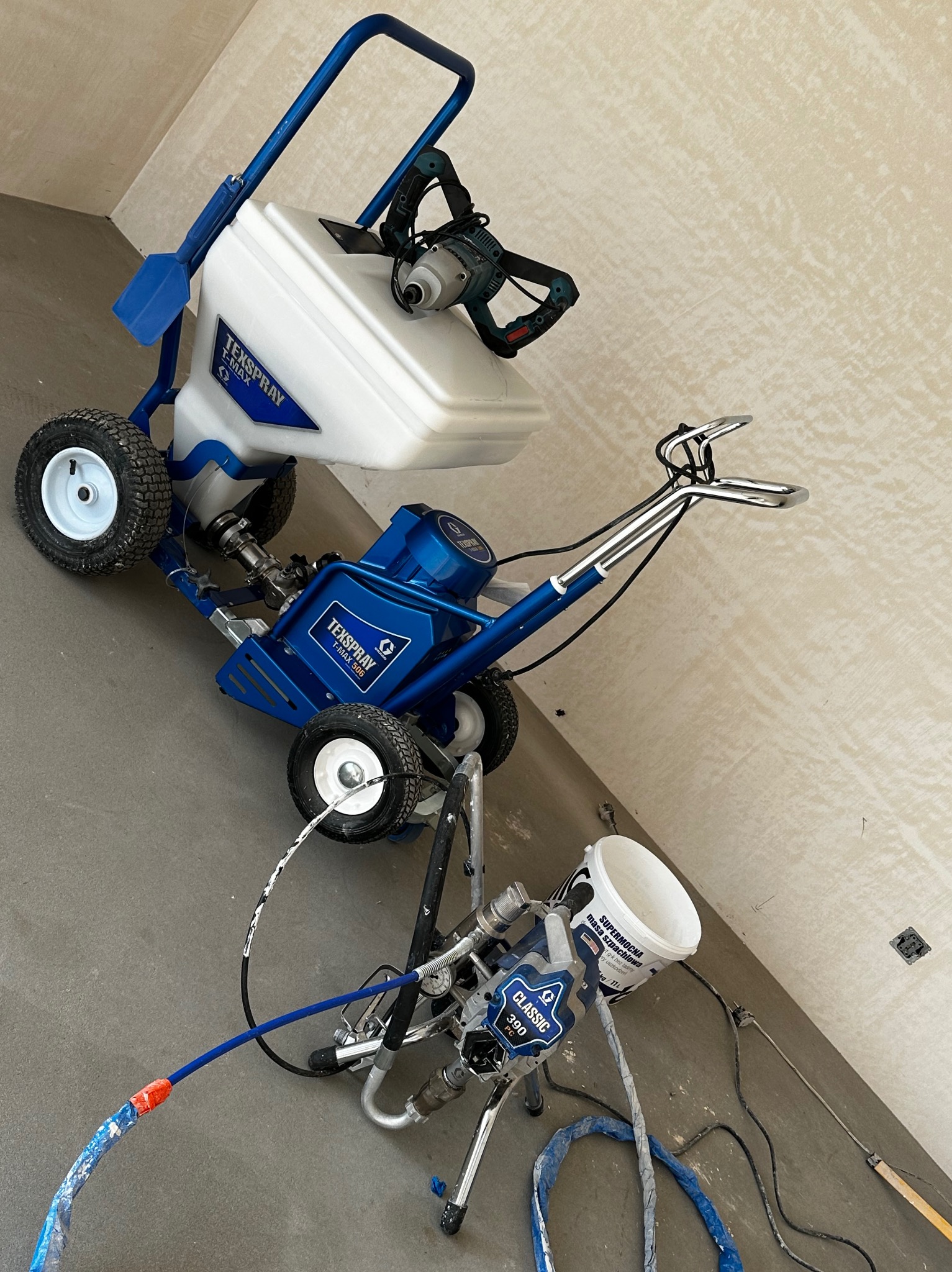 Agregat malarski Texspray T-Max 506 z mikserem i pistolet natryskowy Classic 390 PC, gotowy do aplikacji gładzi na ścianę w surowym wnętrzu.