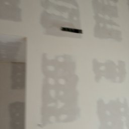 DAR - MAX DARIUSZ NAPIÓRKOWSKI - Ściana po szpachlowaniu płyt kartonowo-gipsowych, widoczne łączenia i niedoskonałości przygotowane do dalszej obróbki, z widocznymi śladami szpachli.