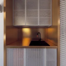 Nowoczesna łazienka z szafkami z perforowanej blachy, czarnym zlewem i złotymi detalami, oświetlona ciepłym światłem.