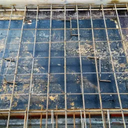 Siatka z prętów zbrojeniowych ułożona na deskowaniu, przygotowana do zalania betonem, widoczne pionowe elementy dystansowe.