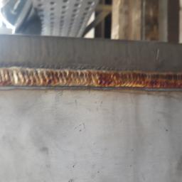 Usługi spawalnicze Roman Migdalek - Zbliżenie na świeżo wykonany spaw na metalowej konstrukcji, widoczne charakterystyczne przebarwienia termiczne.