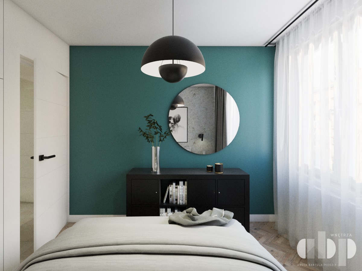 Sypialnia w odcieniach bieli i zieleni z okrągłym lustrem nad czarną komodą, minimalistyczna lampa wisząca, zasłony w oknie.