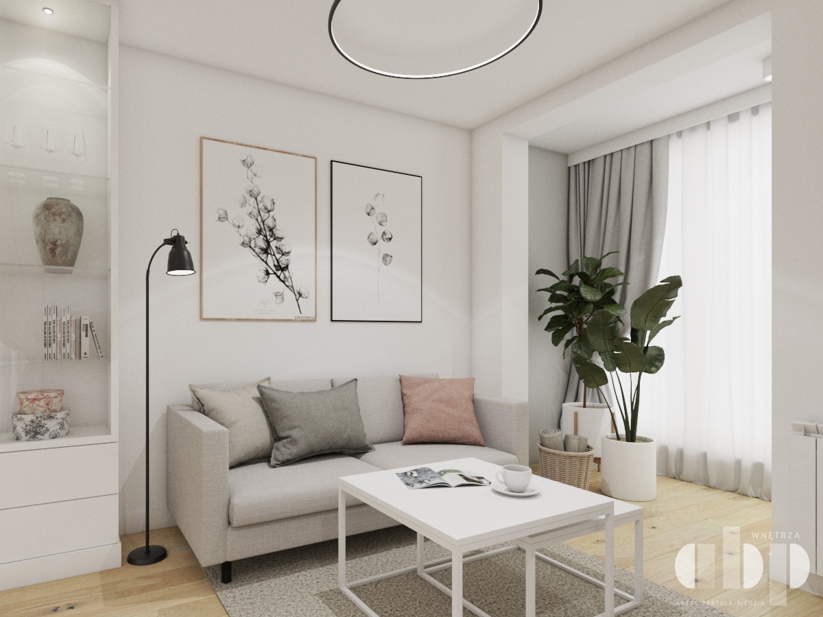 Jasny salon z szarą sofą, białym stolikiem kawowym, czarną lampą podłogową i roślinami doniczkowymi, uzupełniony minimalistycznymi grafikami na ścianie i okrągłą lampą sufitową.