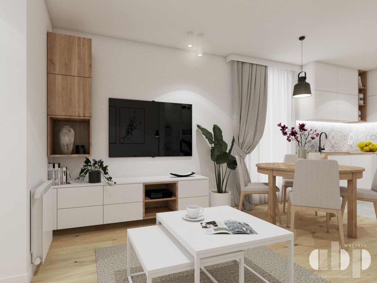 Jasne wnętrze salonu z aneksem kuchennym, drewniana podłoga, białe meble, telewizor na ścianie, okrągły stół z krzesłami, roślina doniczkowa i dekoracje.