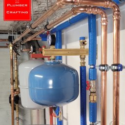 Plumber Crafting - Instalacja CO z miedzianymi i niebieskimi rurami, zbiorniki wyrównawcze, manometry. Widok na fragment instalacji grzewczej w kotłowni.