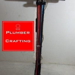 Instalacja podtynkowa: czerwona i niebieska rura prowadzone w bruździe w ścianie, pod stelażem WC. Widoczne łączenia i fragment podłogi.