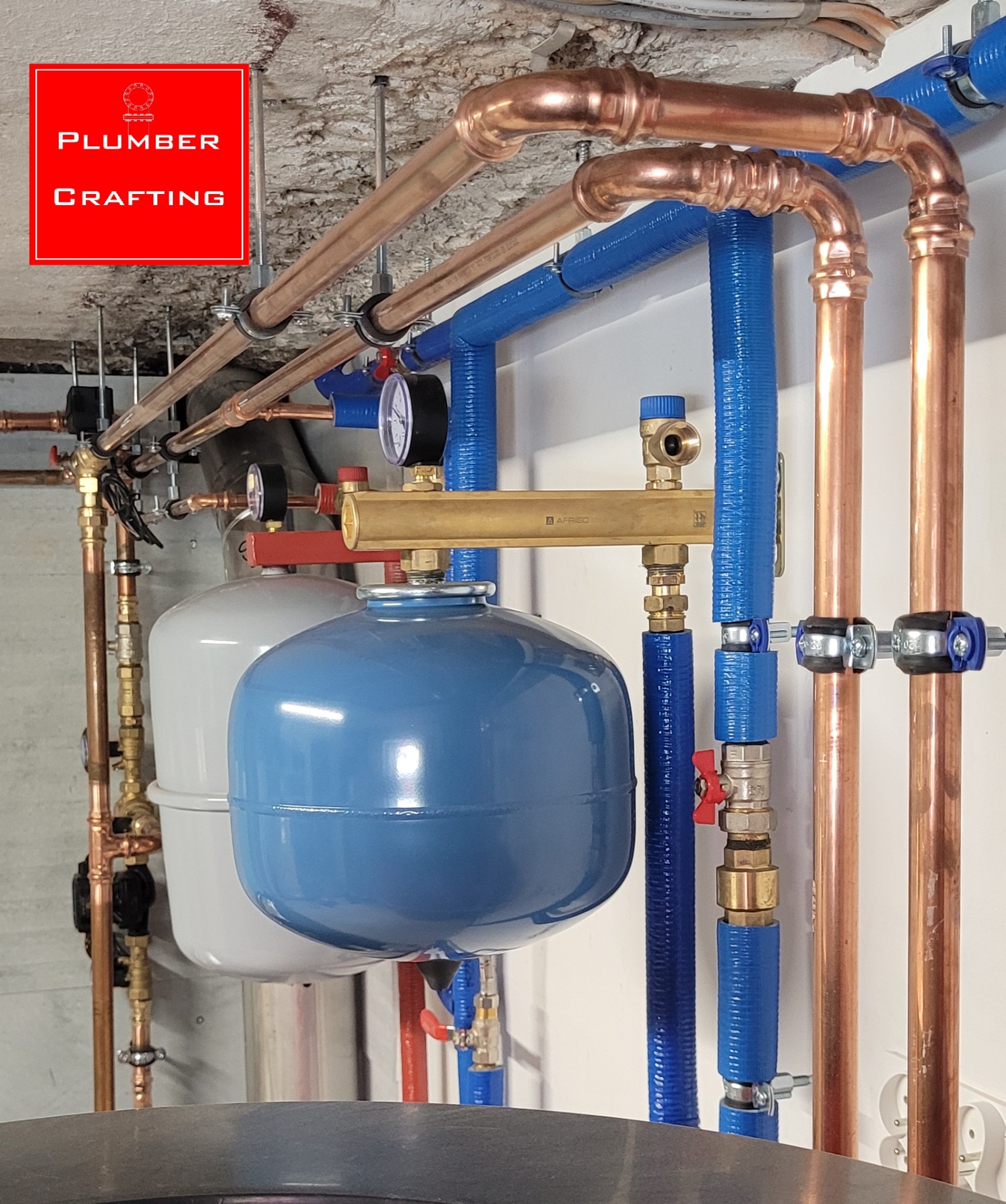 Instalacja CO z miedzianymi i niebieskimi rurami, zbiorniki wyrównawcze, manometry. Widok na fragment instalacji grzewczej w kotłowni.