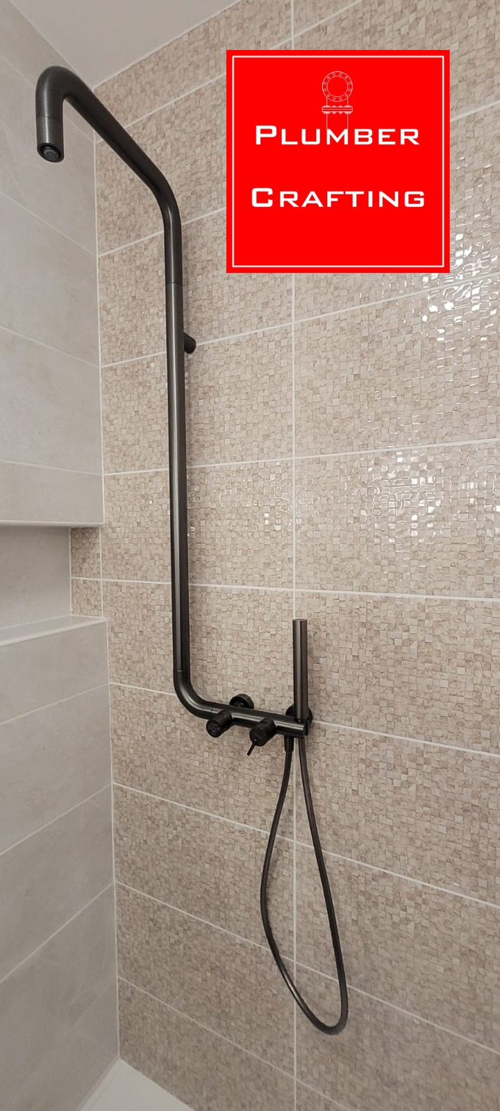 Czarna, nowoczesna bateria prysznicowa zamontowana na ścianie z mozaiką w beżowych odcieniach. Widoczny górny natrysk i słuchawka prysznicowa.