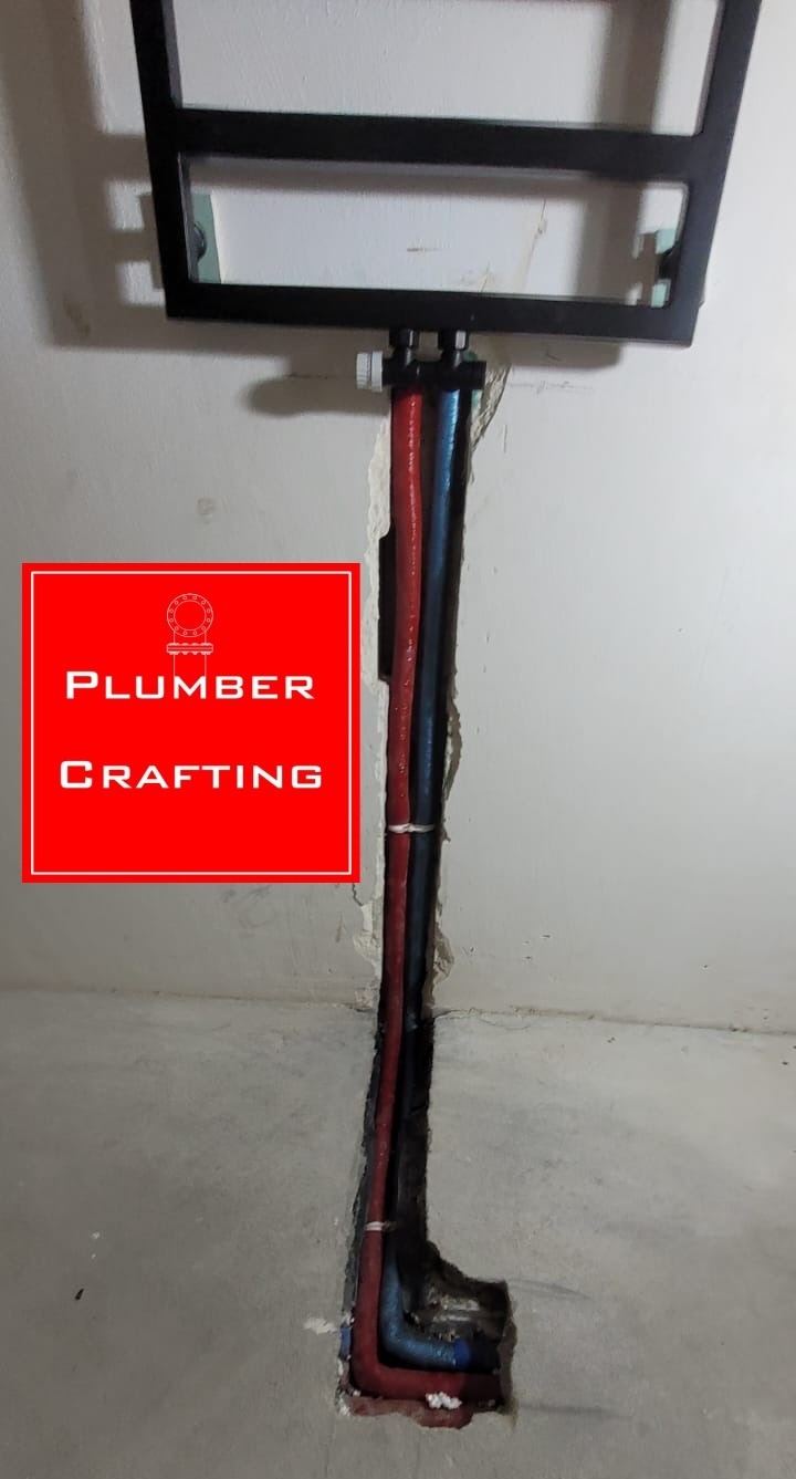 Instalacja podtynkowa: czerwona i niebieska rura prowadzone w bruździe w ścianie, pod stelażem WC. Widoczne łączenia i fragment podłogi.