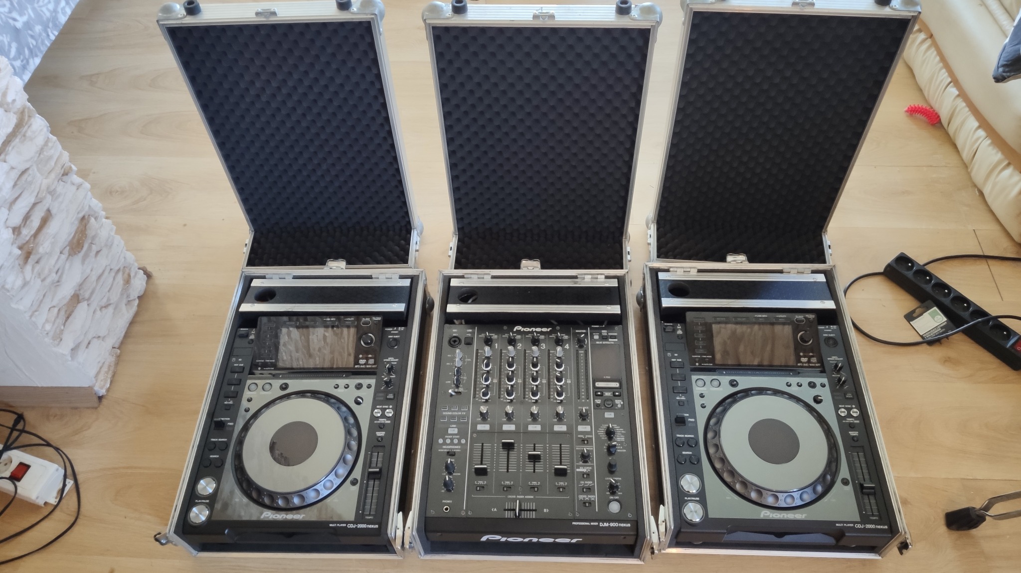 Profesjonalny sprzęt DJ Pioneer: dwa odtwarzacze CDJ-2000 Nexus i mikser DJM-900 Nexus w aluminiowych skrzyniach transportowych z piankowym wnętrzem.