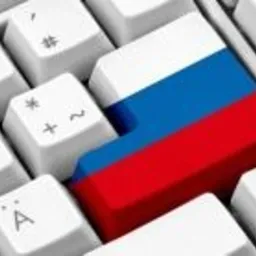 Klawiatura komputera z jednym klawiszem pomalowanym w barwy flagi Rosji, widok z góry pod kątem.