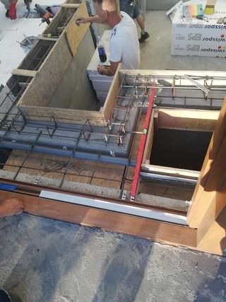 Zbrojenie i szalunek przygotowane pod wylewkę balkonu z zamontowaną ramą okienną i deską elewacyjną, widoczne bloczki betonowe i ocieplenie EPS.