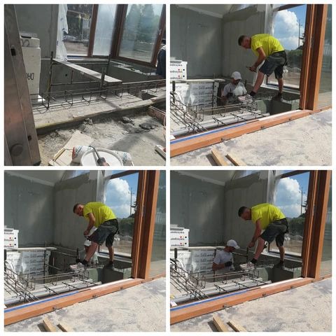 Prace budowlane wewnątrz pomieszczenia z dużym oknem: montaż zbrojenia pod wylewkę, pracownicy w trakcie wykonywania prac, widoczne materiały budowlane i narzędzia.