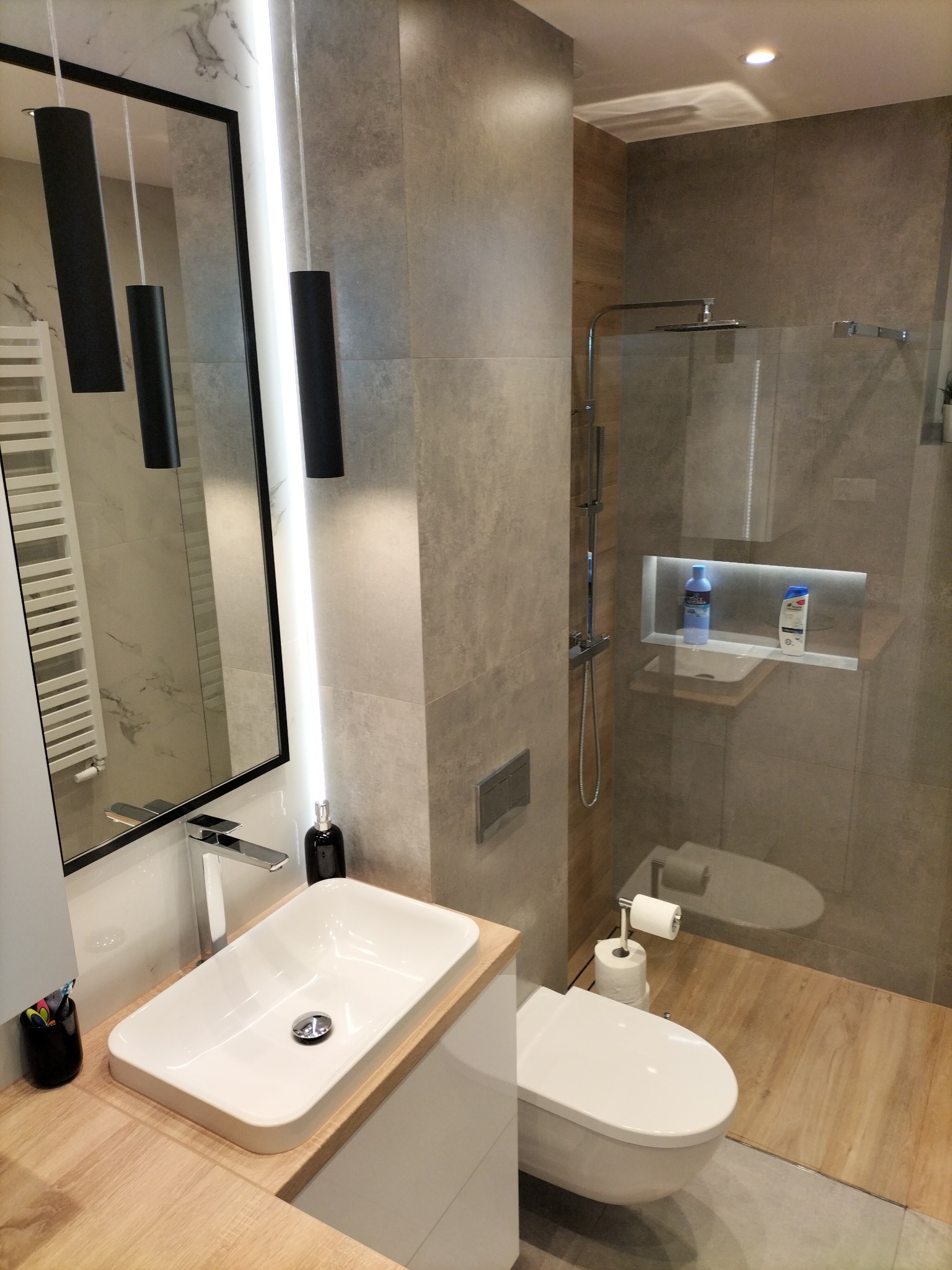 Nowoczesna łazienka w Pile z kabiną prysznicową typu walk-in, umywalką nablatową, dużym lustrem z oświetleniem LED i szarą glazurą.