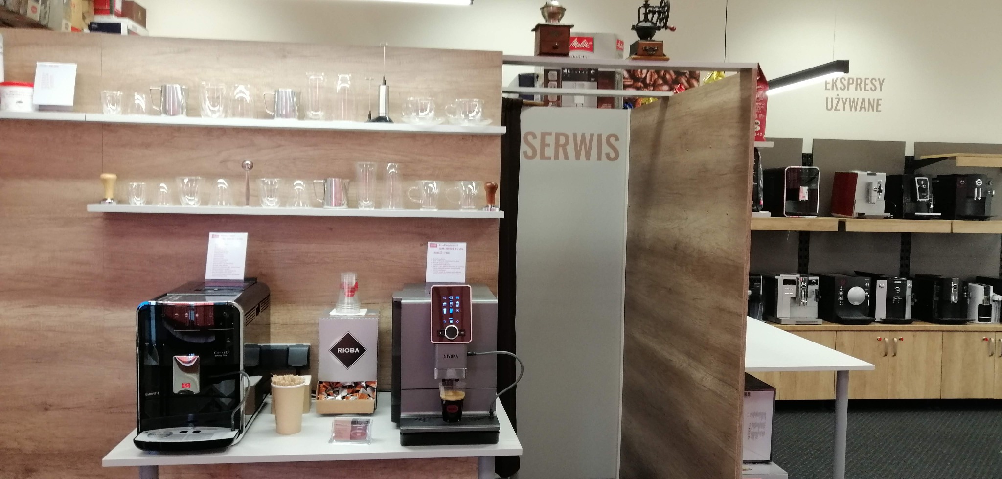 Ekspozycja ekspresów do kawy w sklepie: Melitta, Rioba, Nivona, szklanki na półkach, ekspresy używane w tle.