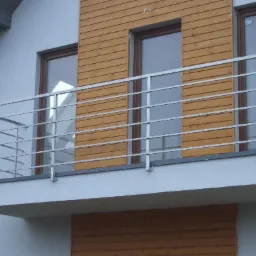 Nowoczesna balustrada balkonowa ze stali nierdzewnej z poziomymi prętami, zamontowana na balkonie domu z drewnianą elewacją.